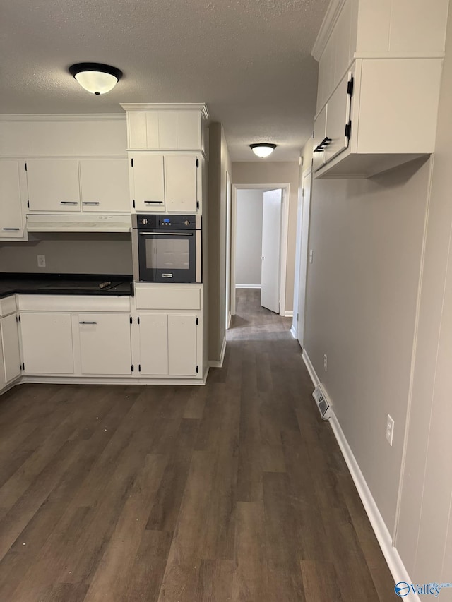 kitchen featuring white cabinets, oven, dark hardwood / wood-style floors, and a textured ceiling