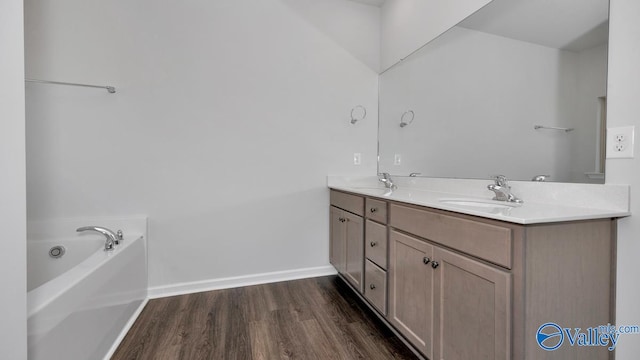 bathroom featuring hardwood / wood-style flooring, vanity, and a washtub