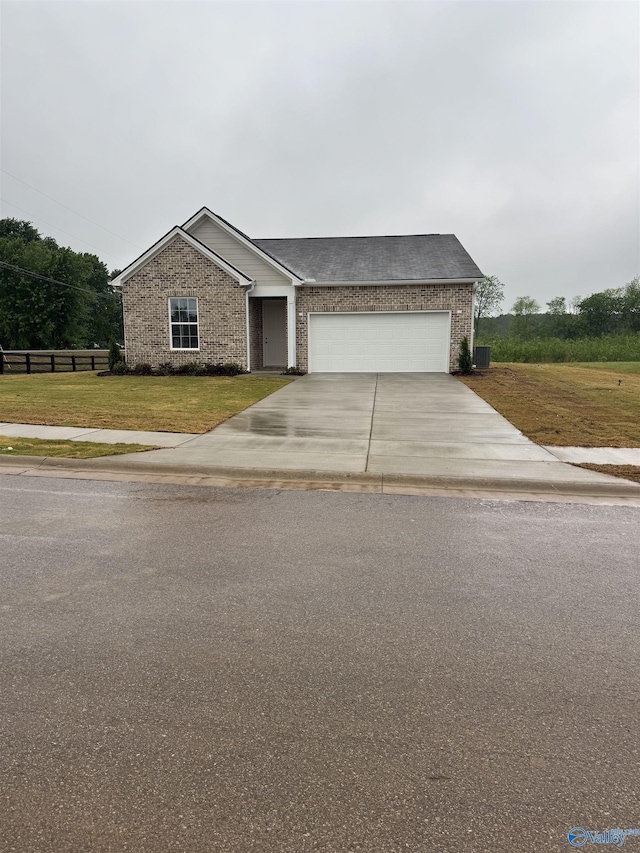 view of front of house featuring fence, driveway, brick siding, a front yard, and a garage