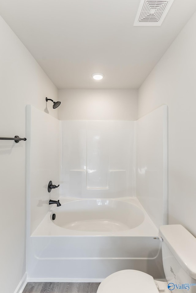 bathroom featuring wood-type flooring, toilet, and bathing tub / shower combination