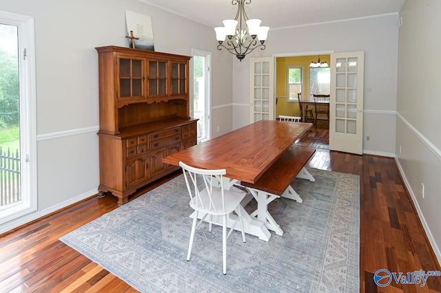 dining area with crown molding, dark hardwood / wood-style flooring, an inviting chandelier, and french doors