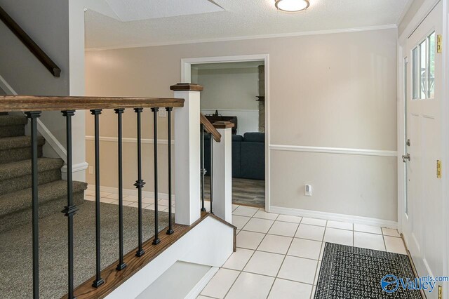 foyer entrance featuring light tile patterned floors, crown molding, and a textured ceiling