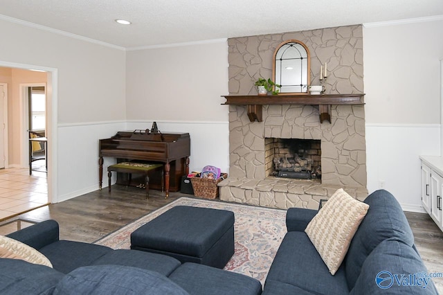 living room with hardwood / wood-style floors, crown molding, a stone fireplace, and a textured ceiling