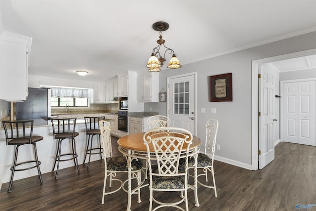 dining room featuring ornamental molding, baseboards, a notable chandelier, and dark wood finished floors