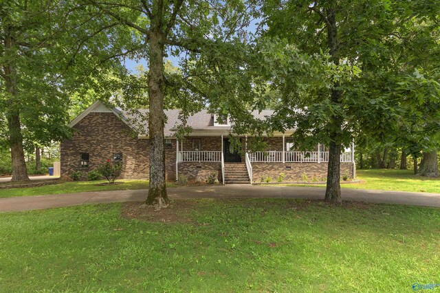 view of front facade with covered porch, brick siding, concrete driveway, and a front lawn