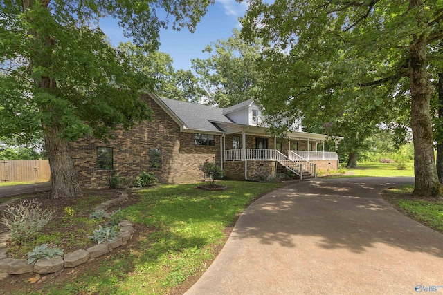 view of front facade featuring driveway, brick siding, a porch, and a front yard