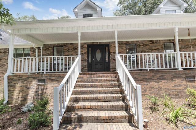 doorway to property with covered porch and brick siding
