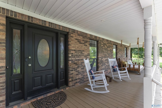 entrance to property featuring brick siding and a porch