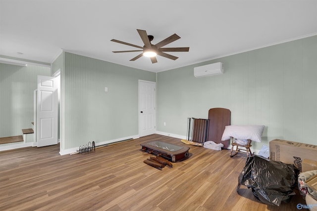 sitting room with ornamental molding, a wall mounted AC, wood-type flooring, and ceiling fan