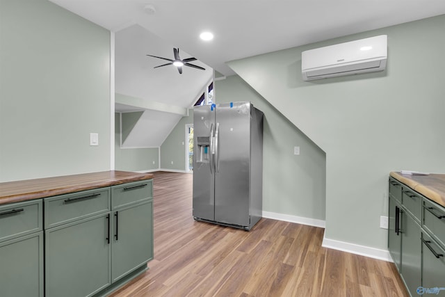 kitchen featuring light wood-type flooring, stainless steel fridge with ice dispenser, a wall mounted air conditioner, and wooden counters