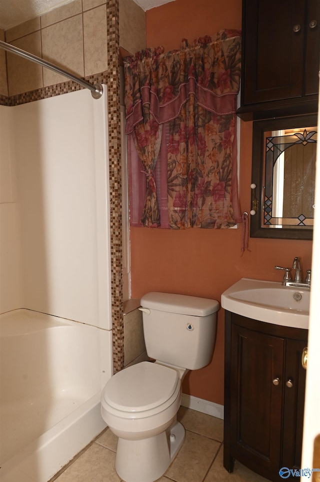 bathroom with vanity, a tile shower, toilet, and tile patterned flooring