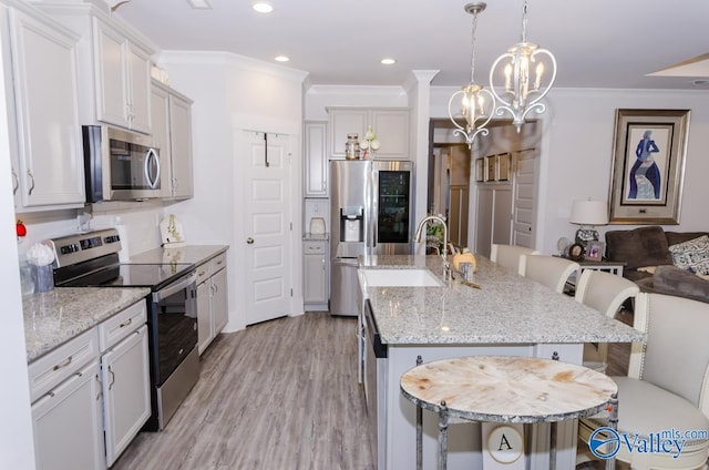 kitchen featuring appliances with stainless steel finishes, a kitchen island with sink, a breakfast bar, white cabinets, and ornamental molding