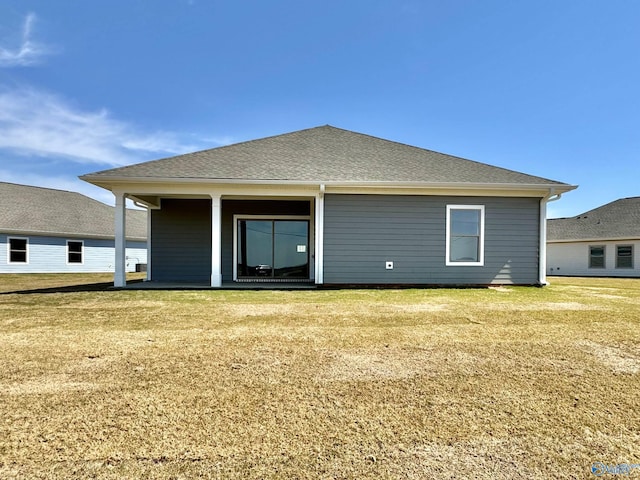 back of property featuring a yard and a shingled roof