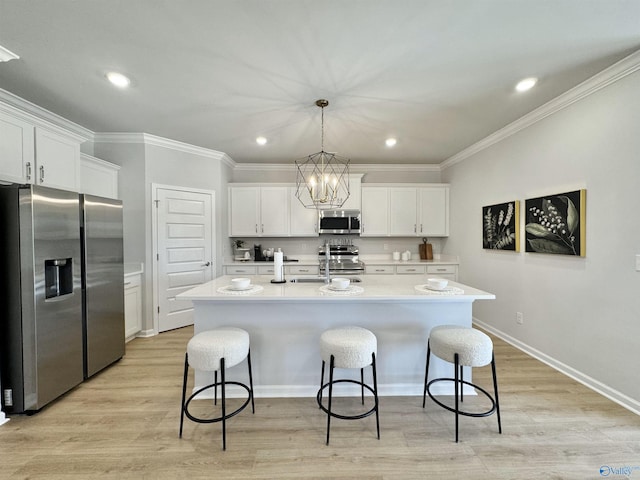 kitchen with a breakfast bar, light countertops, white cabinets, and appliances with stainless steel finishes