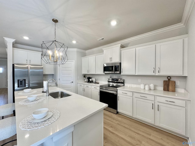 kitchen featuring visible vents, ornamental molding, a sink, appliances with stainless steel finishes, and white cabinetry