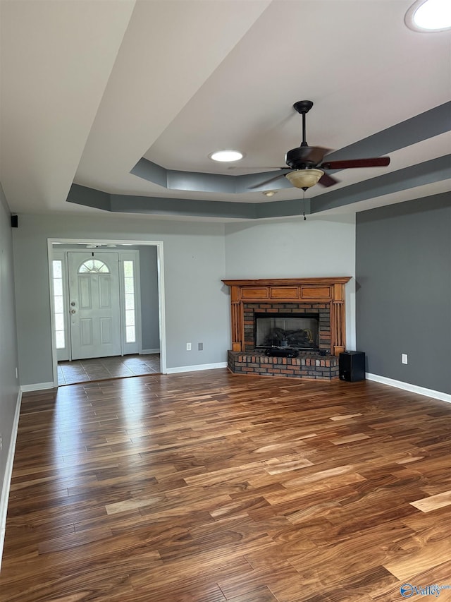 103 Katelyn Dr, Meridianville, AL 35759 - unfurnished living room with a raised ceiling, ceiling fan, wood finished floors, and a brick fireplace