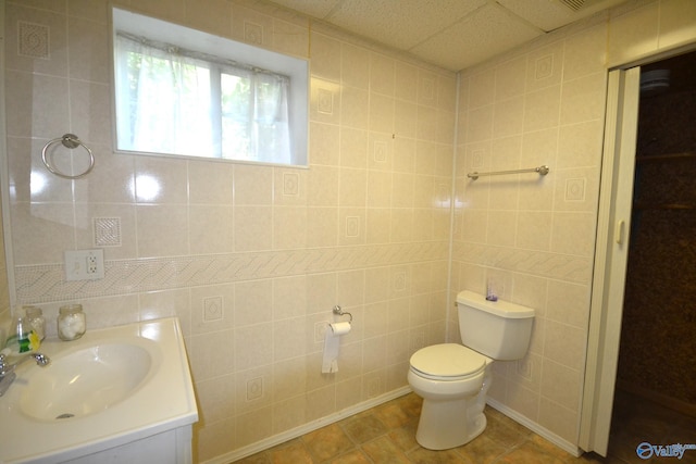 bathroom featuring toilet, tile patterned floors, and tile walls