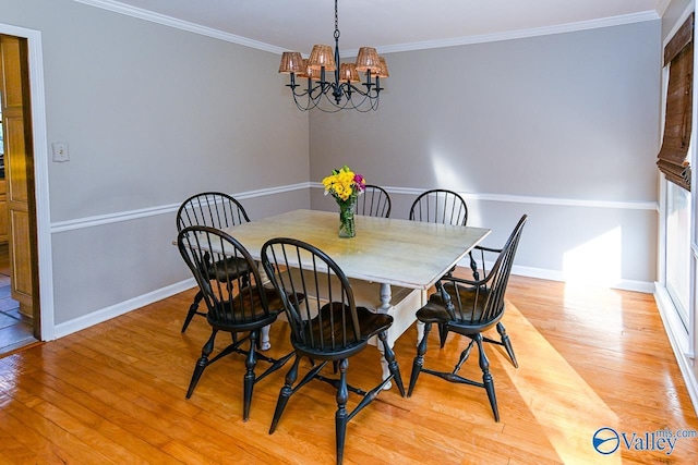 dining room featuring ornamental molding, baseboards, light wood finished floors, and an inviting chandelier