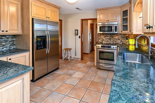 kitchen with light tile patterned floors, visible vents, appliances with stainless steel finishes, light brown cabinets, and a sink