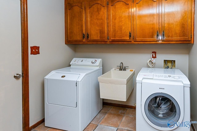 clothes washing area with washing machine and clothes dryer, cabinet space, stone finish floor, a sink, and baseboards