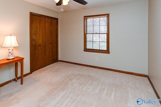 unfurnished bedroom with baseboards, ceiling fan, a closet, and light colored carpet