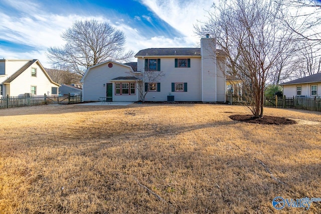 back of house with a chimney, fence, a yard, a patio area, and central AC