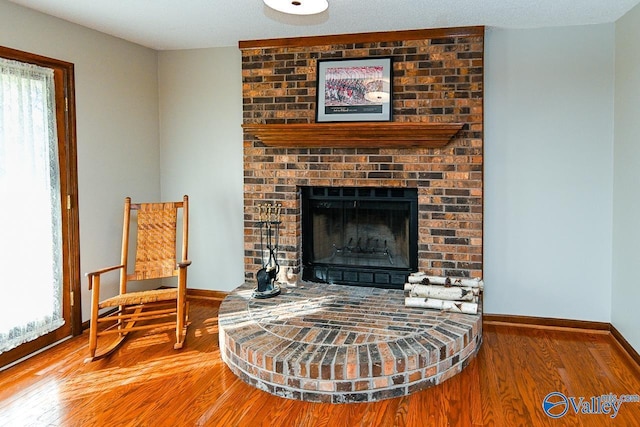 sitting room with a fireplace, baseboards, and wood finished floors