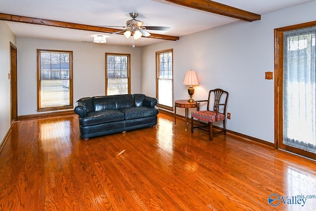 living room featuring a ceiling fan, wood finished floors, beam ceiling, and baseboards