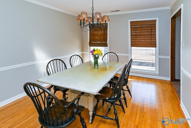 dining room featuring a chandelier, light wood-type flooring, and crown molding