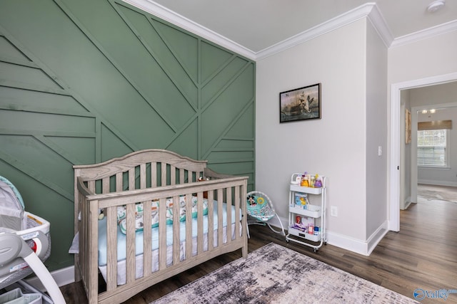 bedroom with a crib, dark hardwood / wood-style floors, and ornamental molding