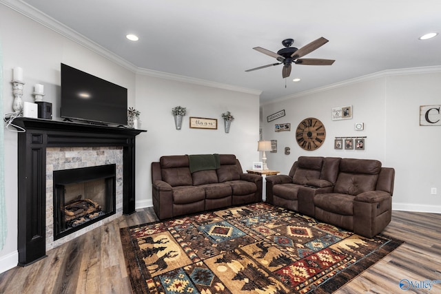 living room with hardwood / wood-style floors, ceiling fan, a fireplace, and crown molding