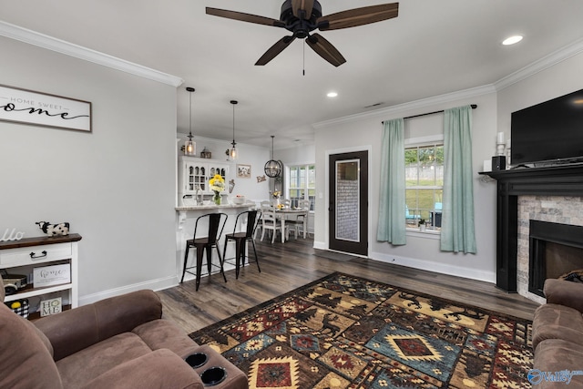 living room with ornamental molding, a stone fireplace, dark hardwood / wood-style floors, bar, and ceiling fan