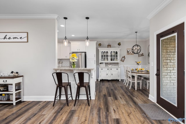 kitchen featuring white cabinets, dark hardwood / wood-style floors, pendant lighting, and stainless steel refrigerator