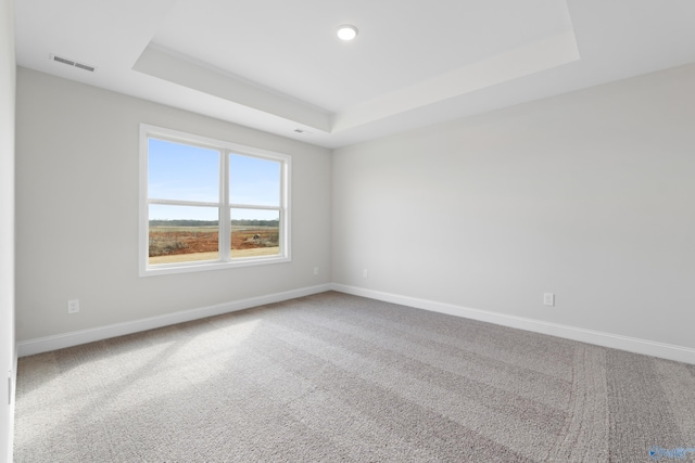 carpeted empty room with a raised ceiling, visible vents, and baseboards