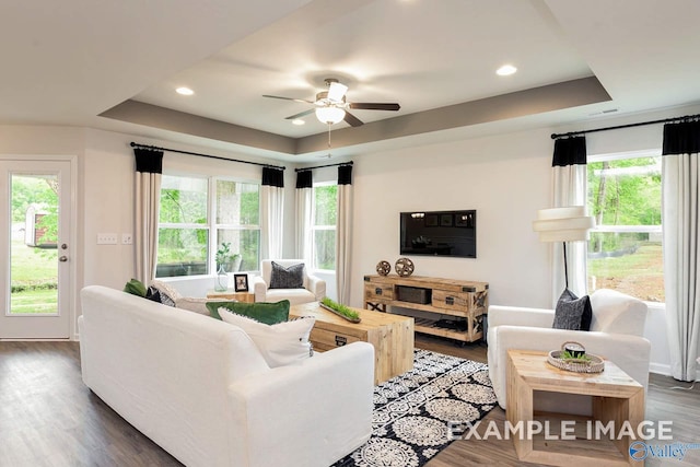 living area with a ceiling fan, a tray ceiling, dark wood finished floors, and recessed lighting