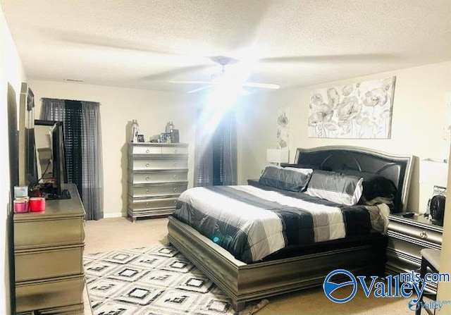 bedroom with a textured ceiling, light colored carpet, and ceiling fan