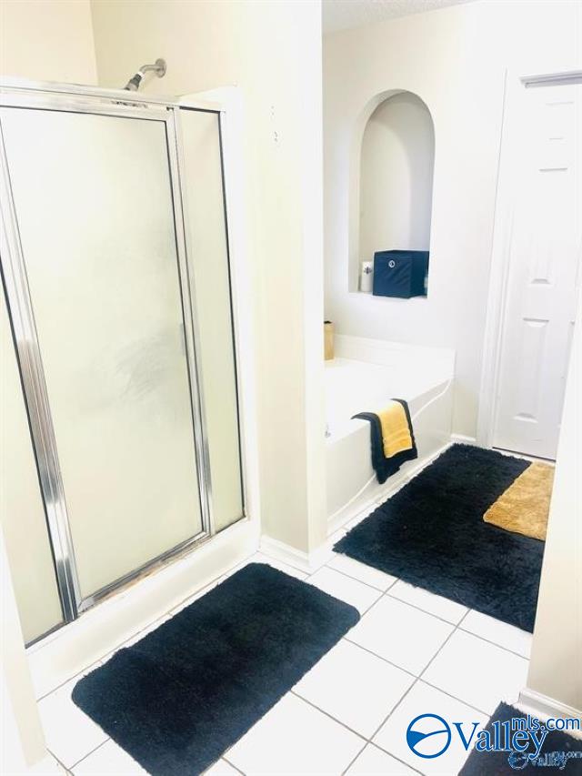 bathroom with independent shower and bath and tile patterned floors