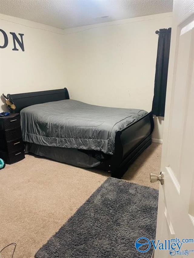 bedroom with ornamental molding, carpet, and a textured ceiling