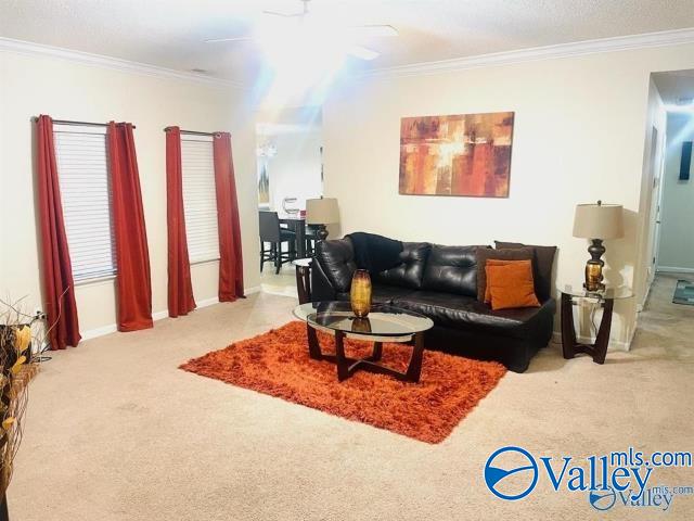 living room with light carpet, ceiling fan, and ornamental molding