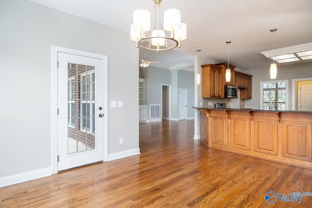 kitchen with a kitchen bar, kitchen peninsula, decorative light fixtures, dark wood-type flooring, and decorative backsplash