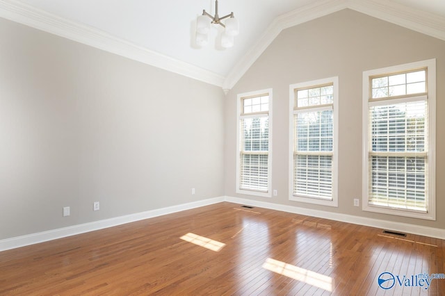 spare room featuring ornamental molding, hardwood / wood-style floors, high vaulted ceiling, and a chandelier