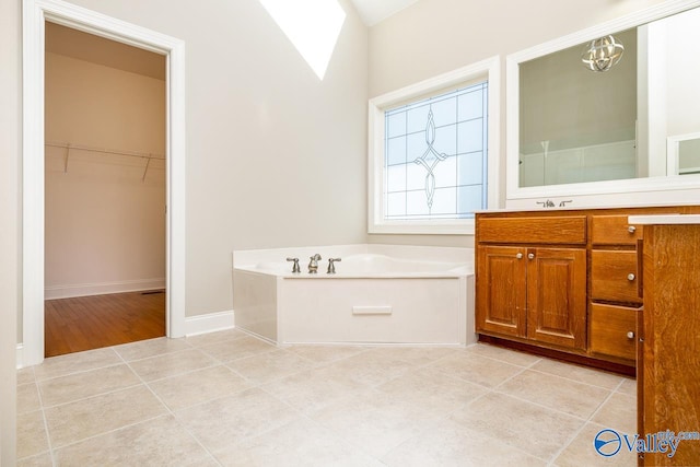 bathroom with lofted ceiling, a tub, an inviting chandelier, vanity, and tile patterned flooring