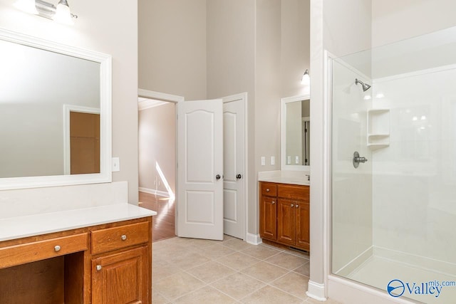 bathroom with vanity, a towering ceiling, tile patterned floors, and a shower with shower door