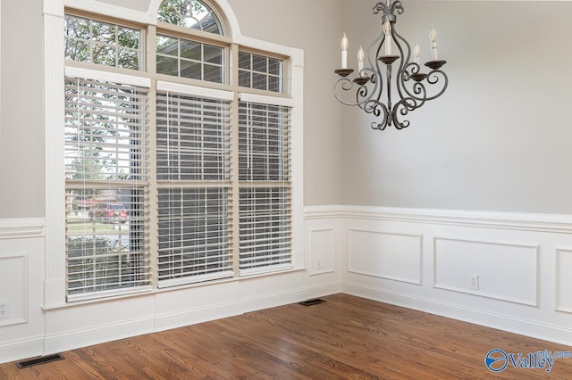 unfurnished dining area with a chandelier and wood-type flooring