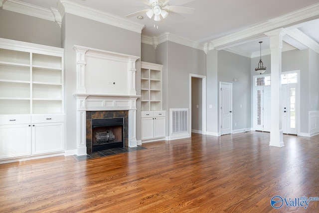 unfurnished living room featuring ornate columns, a tiled fireplace, dark hardwood / wood-style floors, crown molding, and ceiling fan