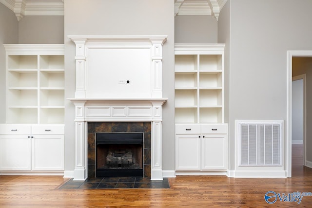 unfurnished living room with ornamental molding, a tile fireplace, and dark hardwood / wood-style flooring