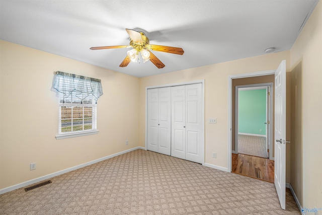 unfurnished bedroom featuring a closet, light colored carpet, and ceiling fan