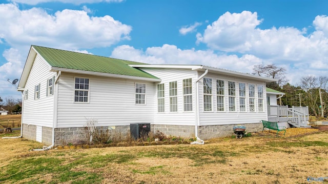 view of side of home with a yard, central AC unit, and a wooden deck