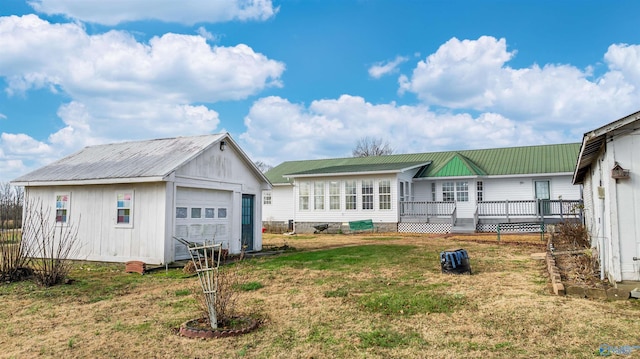 back of house with a yard, a garage, and an outdoor structure