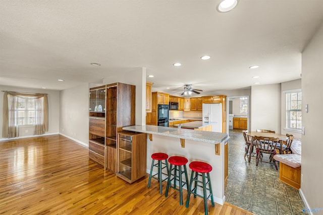 kitchen featuring kitchen peninsula, a kitchen breakfast bar, a healthy amount of sunlight, and black appliances